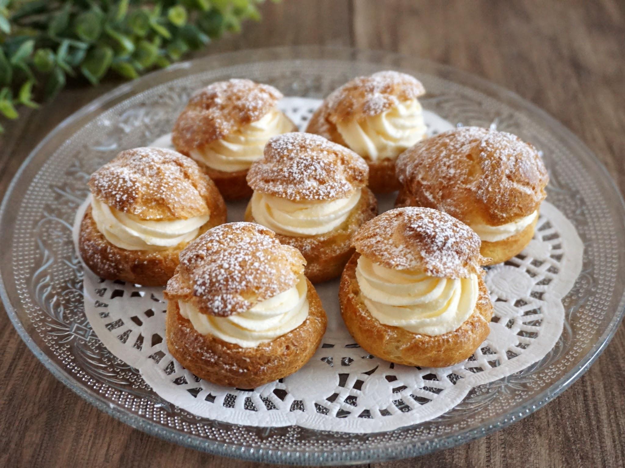A plate of Japanese shuu-cream cream puffs, filled with custard and topped with powdered sugar.